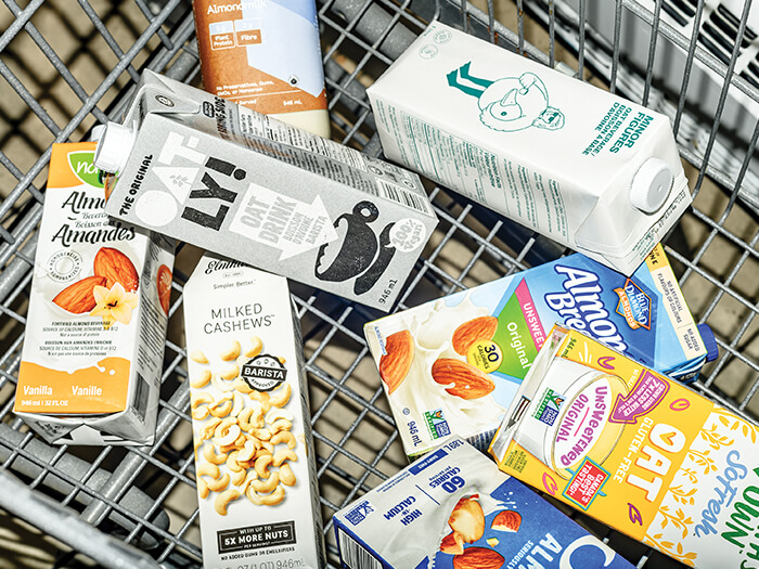 Several cartons of non-dairy milk are shown from above in a grocery cart