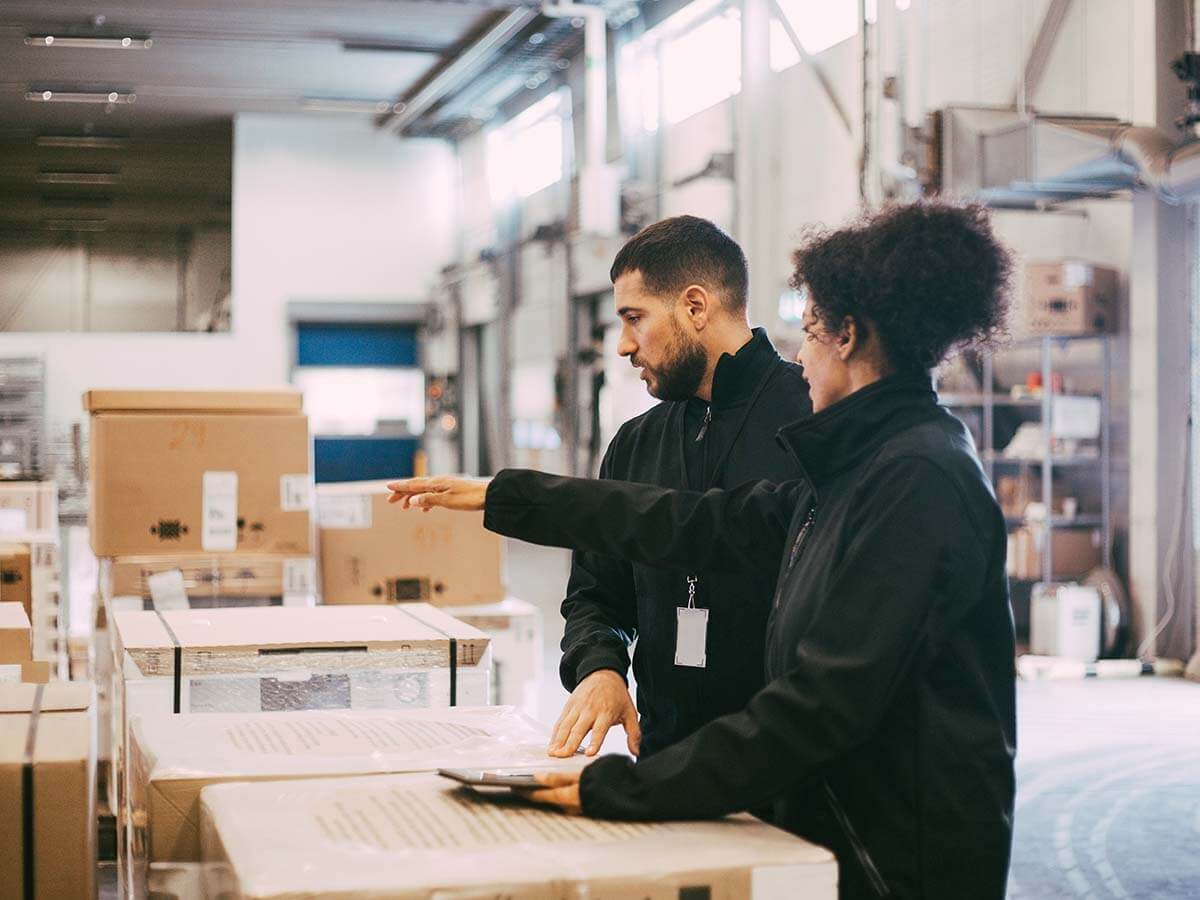 Businesswoman pointing while discussing with male colleague at warehouse