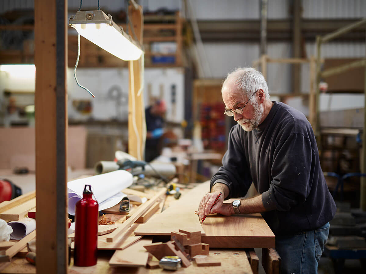 Artisan marquant des mesures sur un morceau de bois dans un atelier