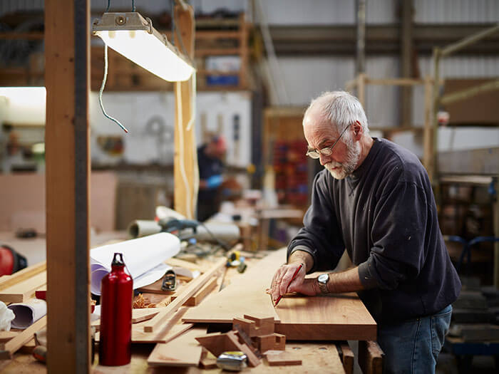 Artisan marquant des mesures sur un morceau de bois dans un atelier