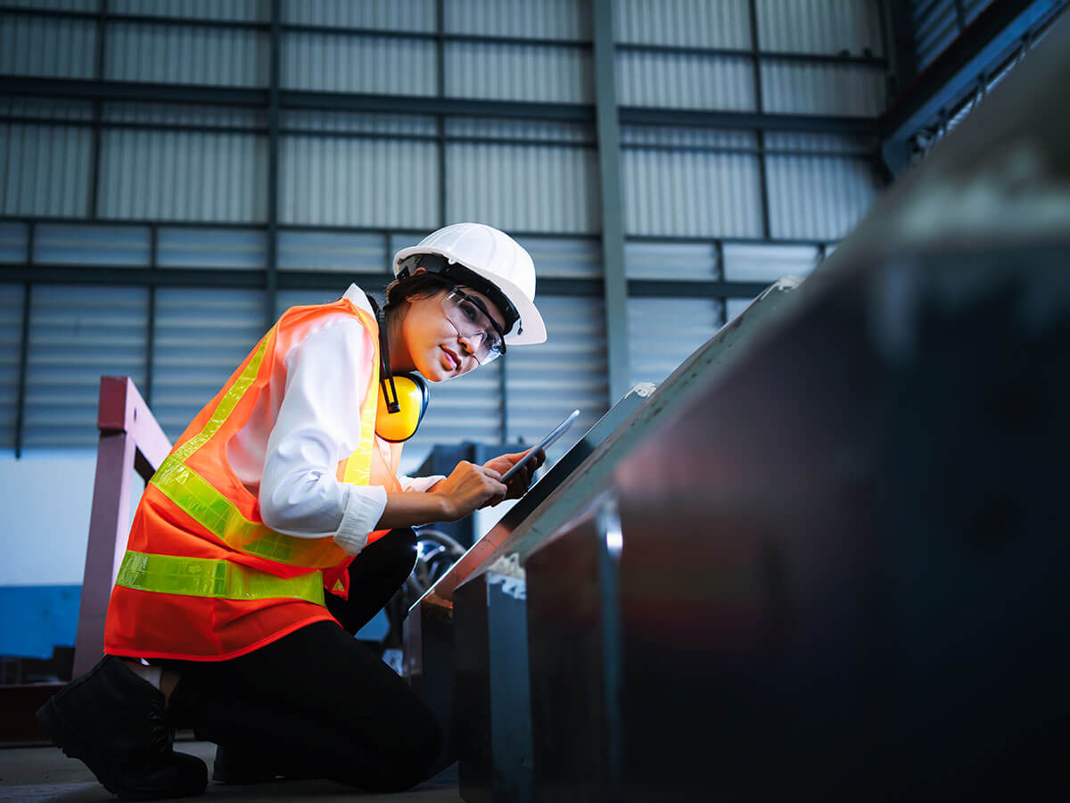 Femme ingénieur inspectant des équipements dans une usine d'acier.