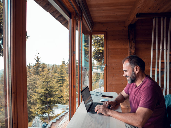 Man working on a laptop from cabin in the woods
