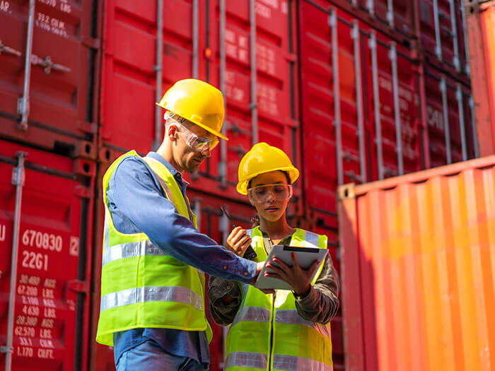 Two workers stand in front of cargo containers