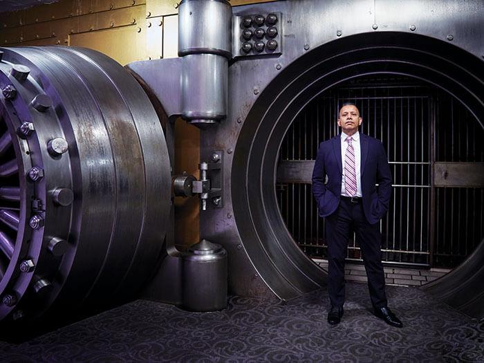 A businessman stands in front of a vault