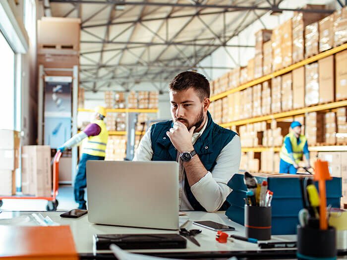 Un homme est montré en train d'utiliser un ordinateur portable dans un entrepôt.