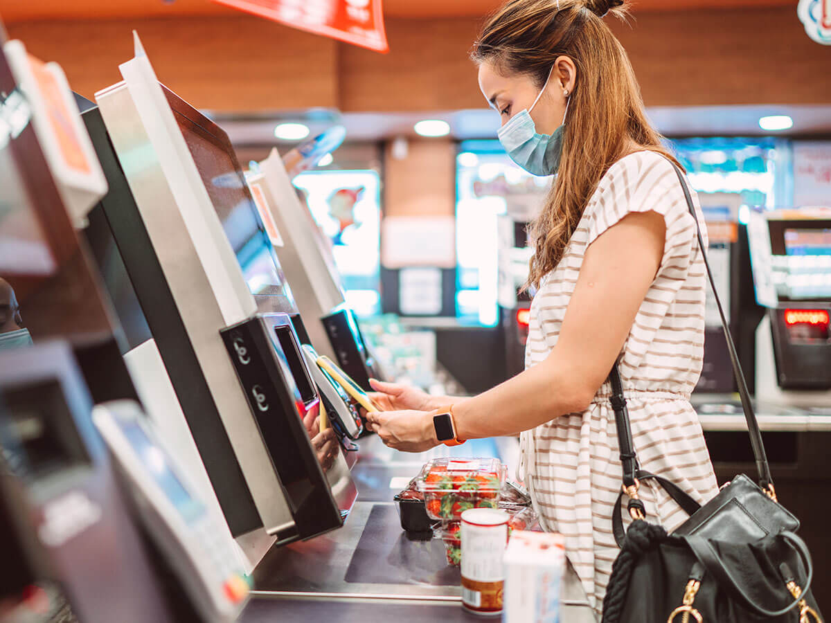 Une femme scanne ses courses à la caisse automatique.