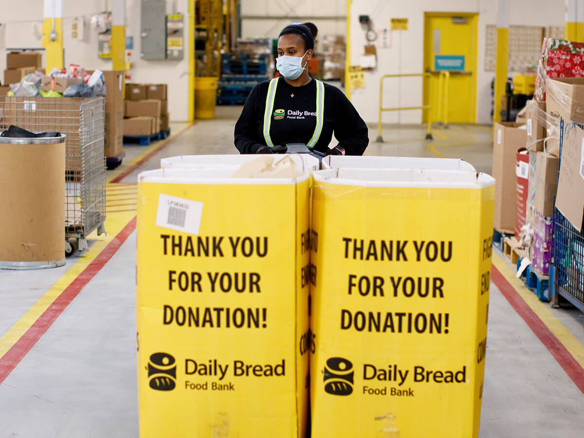 A worker stands in a warehouse with donated food items. 