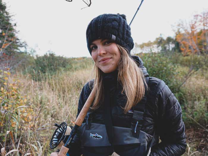 A woman holds a fishing rod outdoors