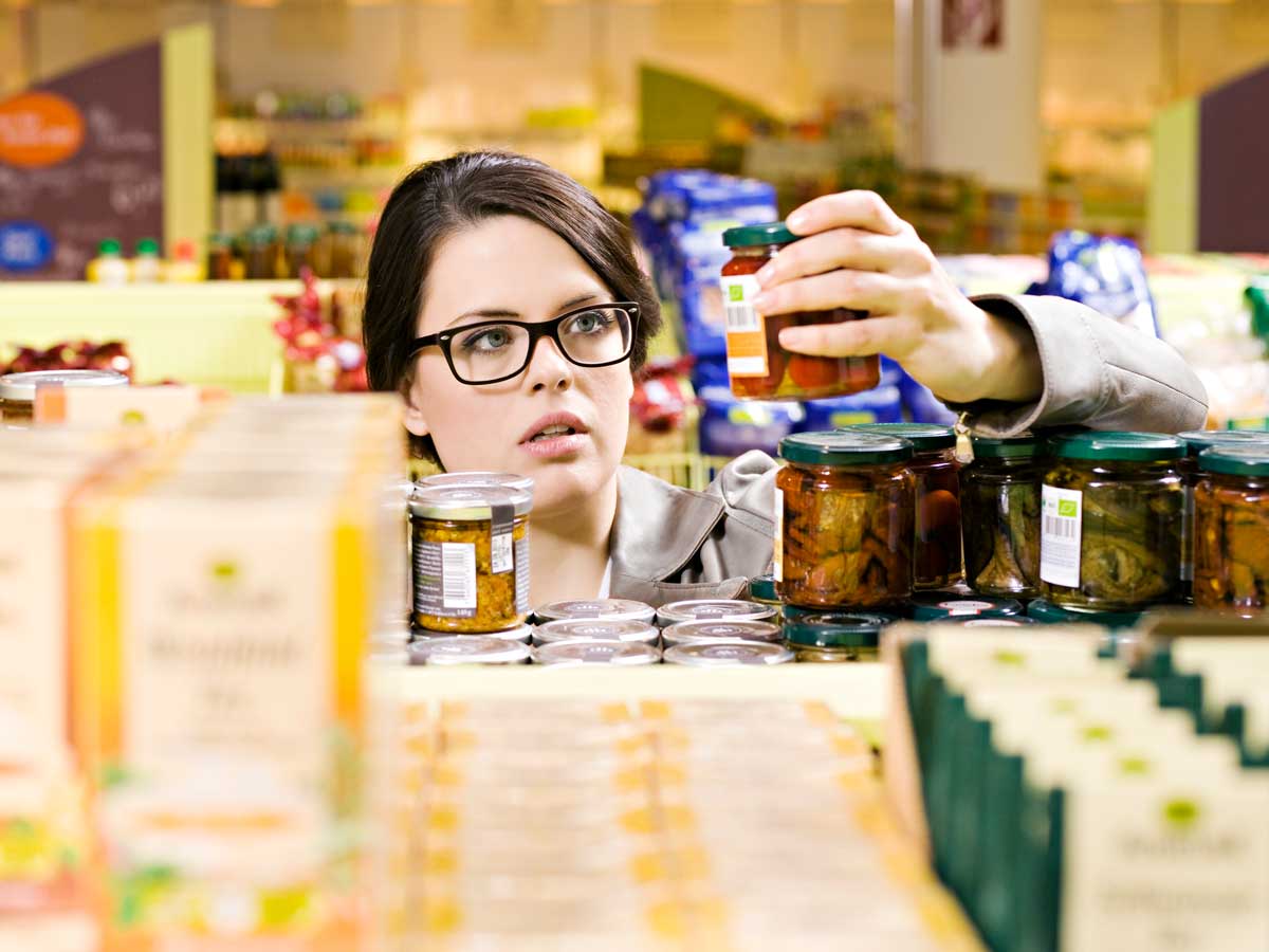 Une femme examine des bocaux dans une épicerie.