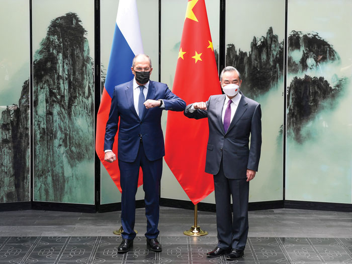 Un officiel russe et un officiel chinois qui portent des masques se saluent du coude.