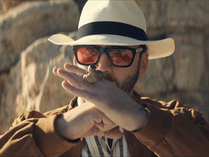 Actor Nicholas Cage is shown wearing a hat and sunglasses in the desert