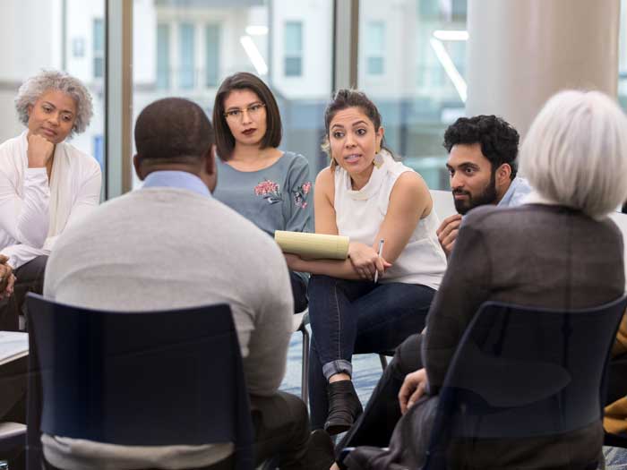 A group sits in a circle to hold a discussion