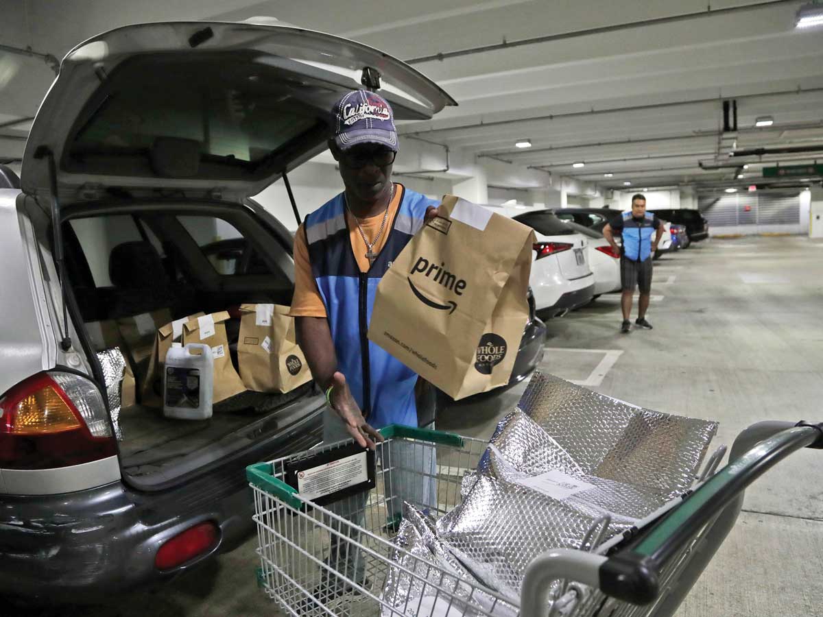 An Amazon worker loads fresh groceries into his car  