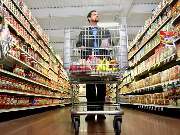 Un homme pousse un chariot d'épicerie dans un supermarché