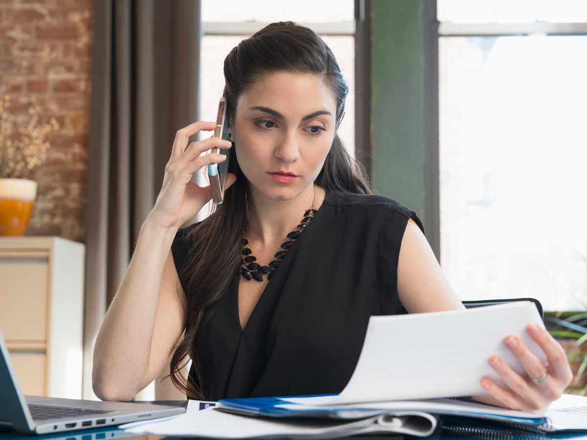 Femme d'affaires caucasienne parlant au téléphone portable dans un bureau