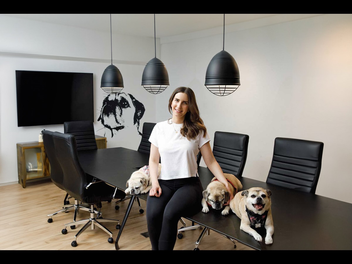Jacqueline Prehogan est assise sur son bureau avec trois chiens