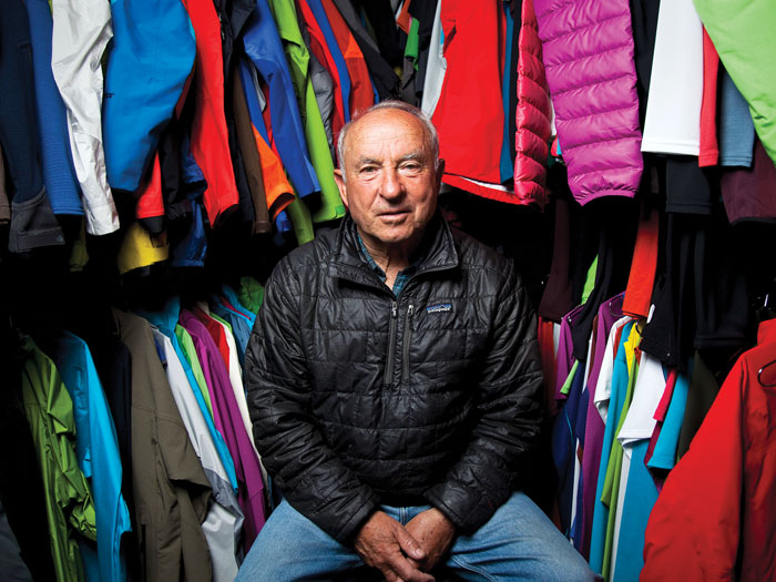 Yvon Chouinard, fondateur de Patagonia, est assis parmi des vêtements de son entreprise et regarde l'appareil photo