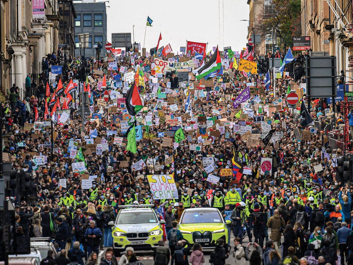 Un grand groupe de personnes tenant des pancartes et manifestant lors de la conférence des Nations Unies sur le changement climatique en 2021.