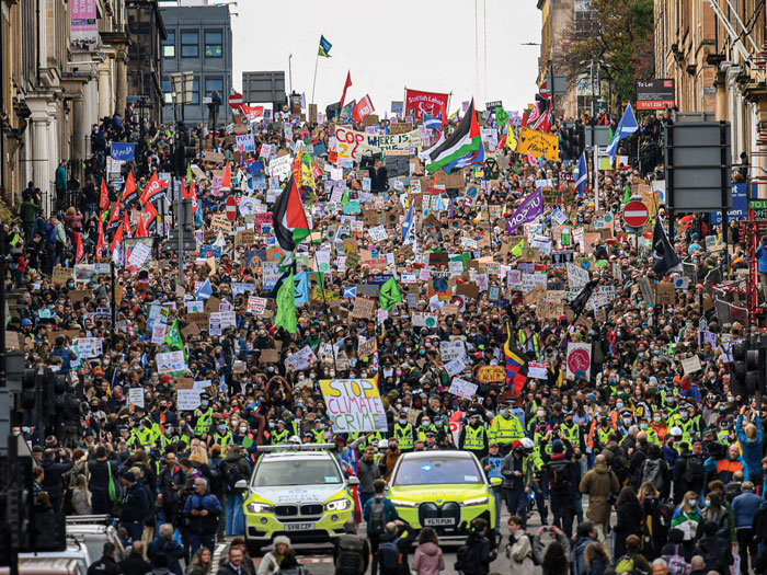Un grand groupe de personnes tenant des pancartes et manifestant lors de la conférence des Nations Unies sur le changement climatique en 2021.