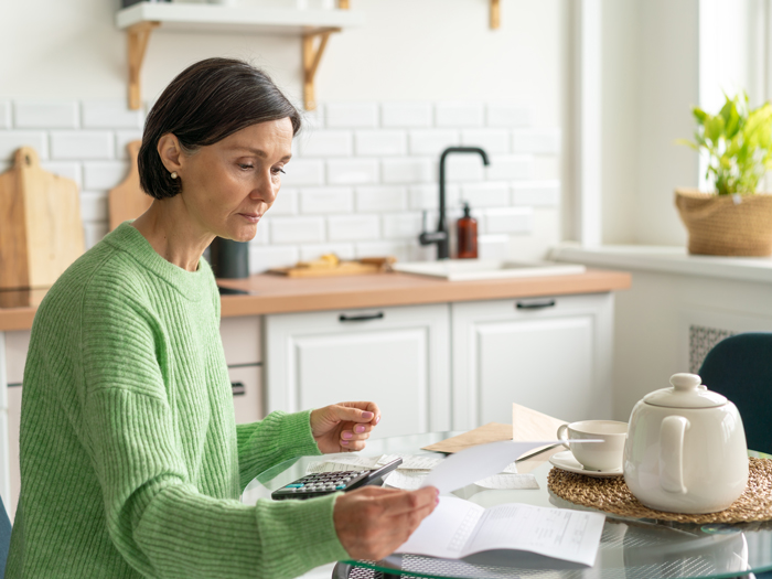 Woman sorting paperwork at kitchen table