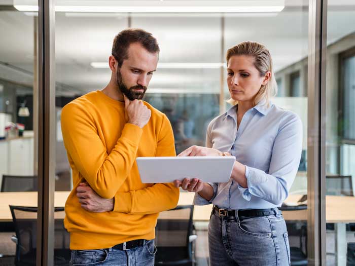 Un homme d'affaires, la main sur le menton, regarde une tablette PC tenue par un collègue dans un bureau