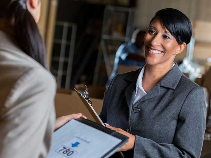 Businesswoman talks with customer in distribution warehouse