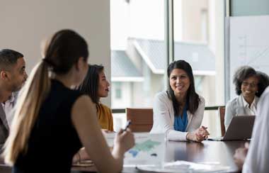 Mid adult Asian businesswoman talks with colleagues during weekly meeting