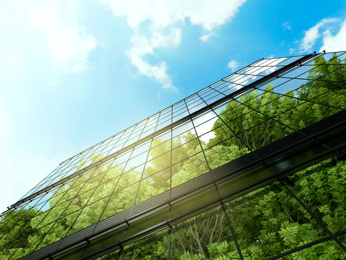 Reflet d’arbres et du ciel sur la représentation en 3D d’un immeuble de bureaux.