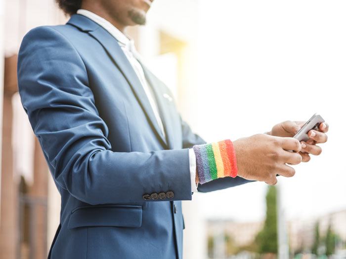 A corporate employee with a Pride wristband uses their smartphone outdoors