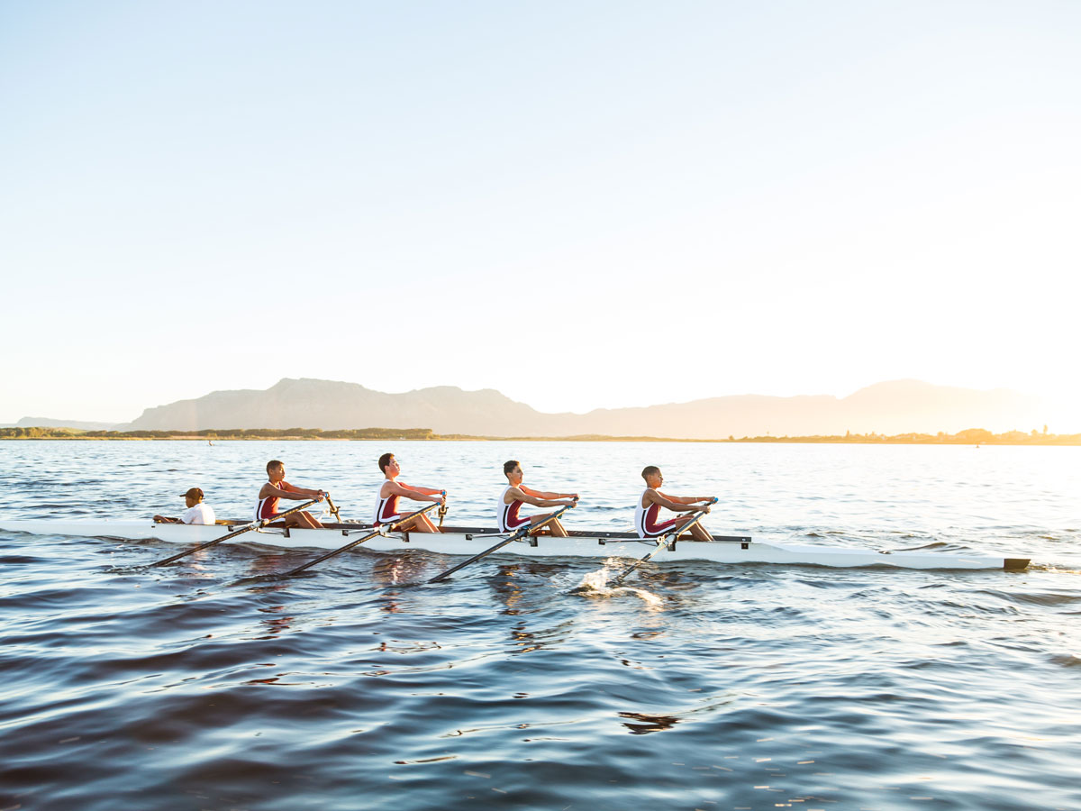A mixed race rowing team training on a lake at dawn 