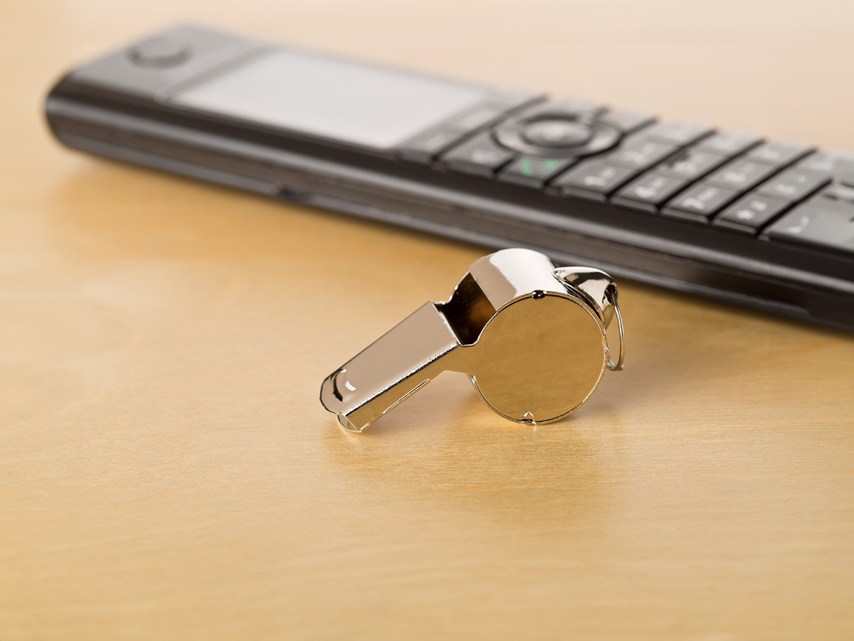 Chrome whistle with telephone on wooden office desk 