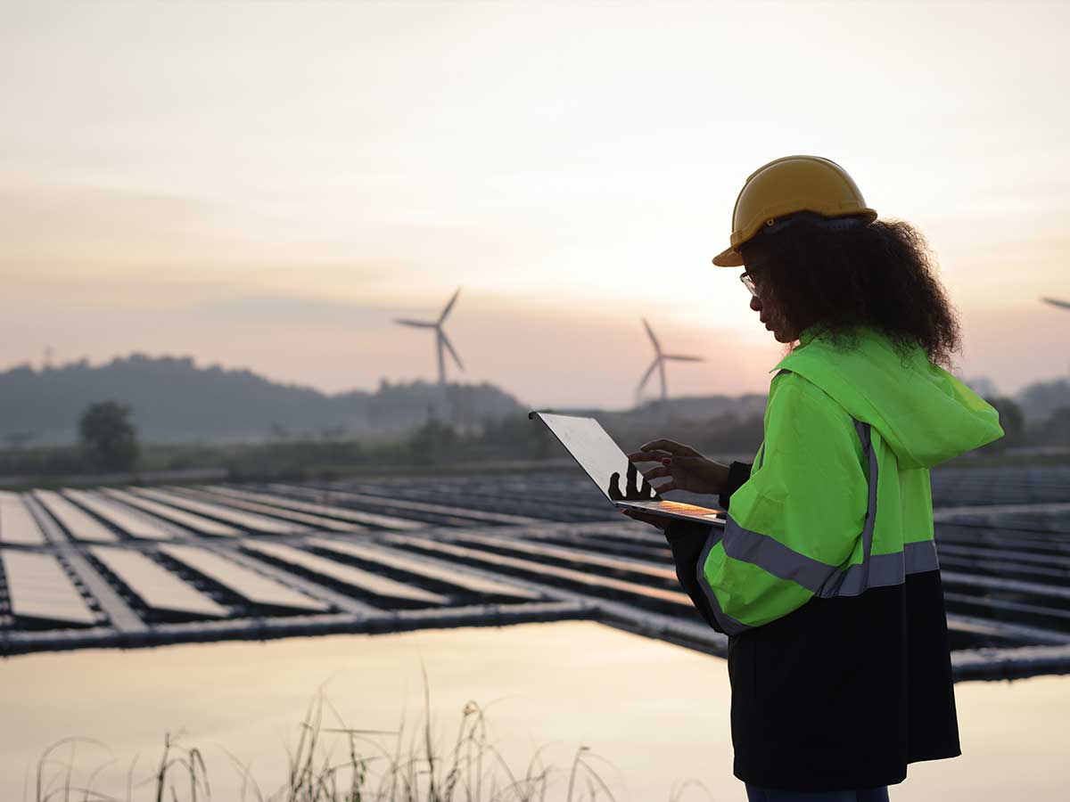 Worker using laptop on site of floating solar farm