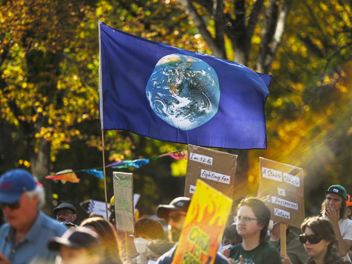 A climate protest march with a flag showing the Earth prominently featured.