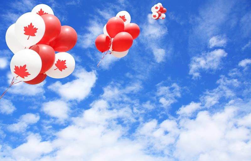 Ballons rouges et blancs à l’effigie du Canada sur fond de ciel bleu.