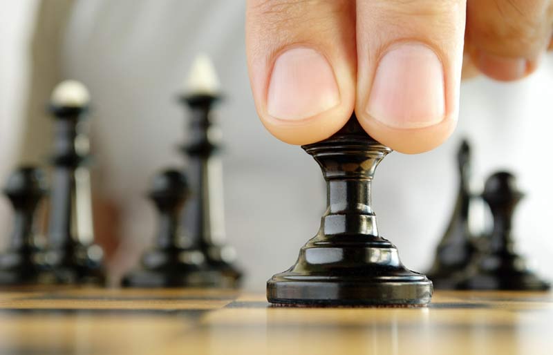 A close-up view of two fingers on a black chess piece.