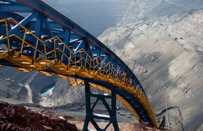 An ore conveyor stretches down into an open pit mining operation.