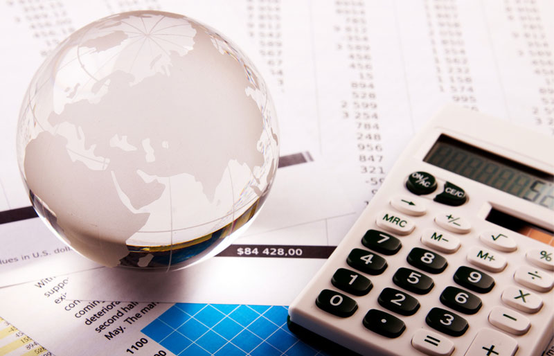A glass globe paperweight and a calculator sit on an assortment of report printouts.