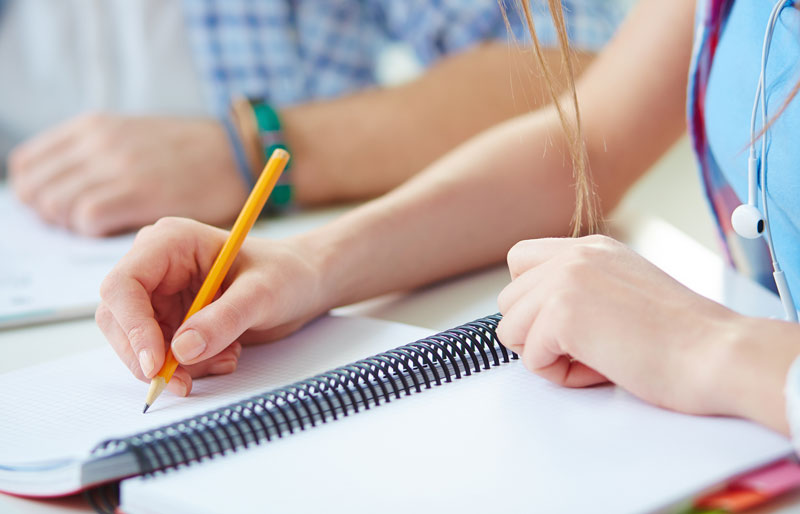 Deux élèves de 4e et 5e année du secondaire prennent des notes dans un cahier durant un atelier de littératie financière sur l’établissement d’objectifs.