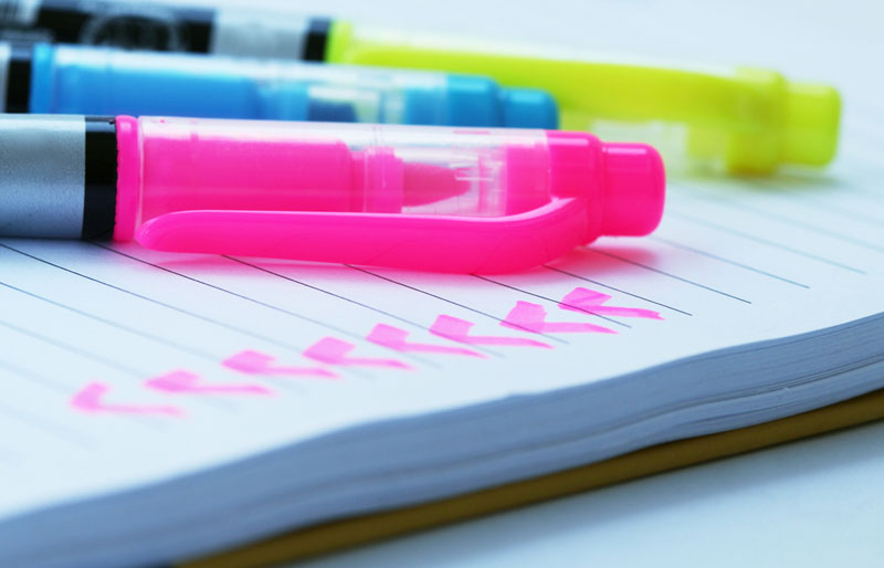 This is a photograph of various coloured markers on a notepad. 