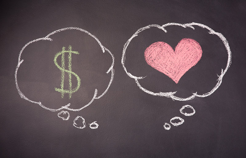 Chalkboard drawing containing two speech bubbles drawn in chalk, one containing a money symbol and the other a heart