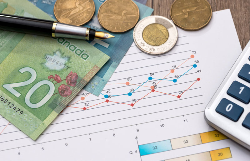 Photo de pièces et de billets de monnaie canadienne, d’un stylo, d’une calculatrice et d’un document avec des graphiques.
