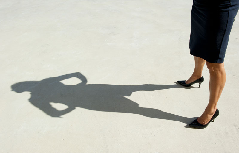 Cadrage sur l’ombre d’une femme d’affaires qui se tient les mains sur les hanches.