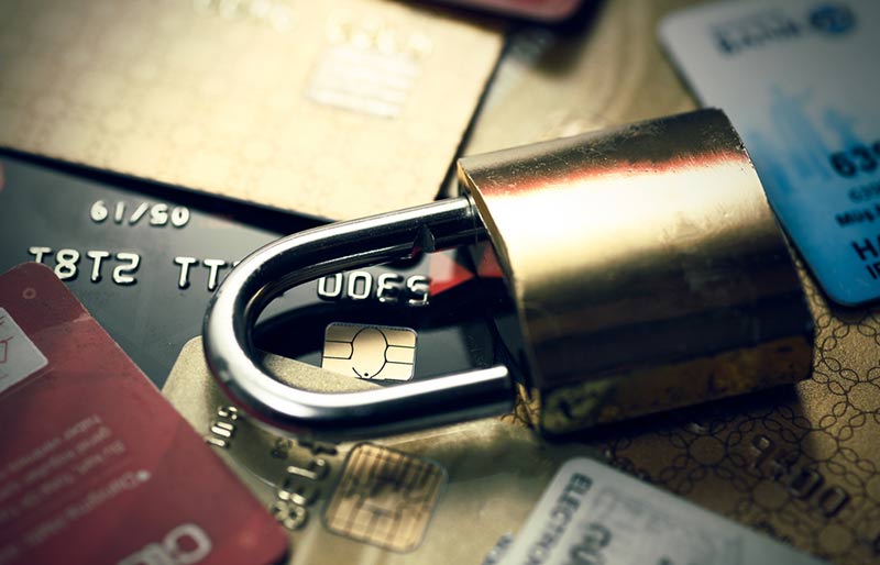 Un cadenas repose sur un tas de cartes de crédit et de débit en désordre.