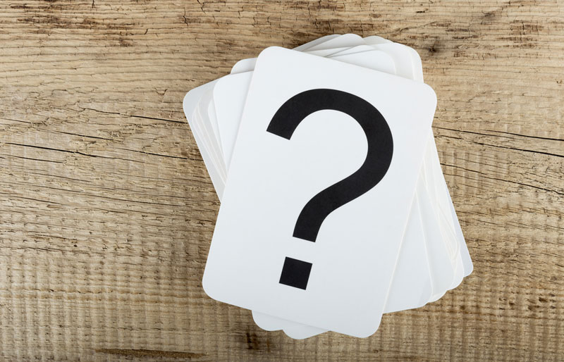 question mark on deck of white cards on wood background