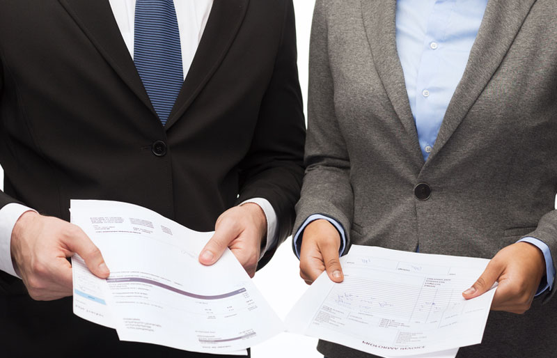 A picture of two business professionals holding various reports. 