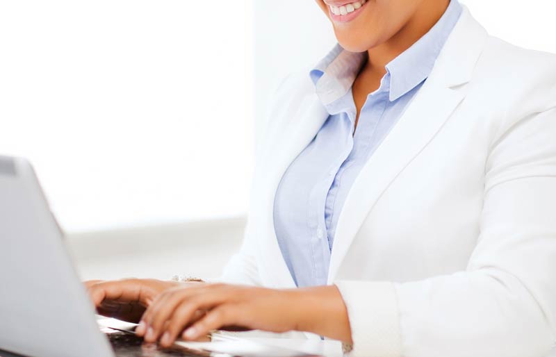Une professionnelle assise à son bureau tape sur le clavier de son ordinateur portable.