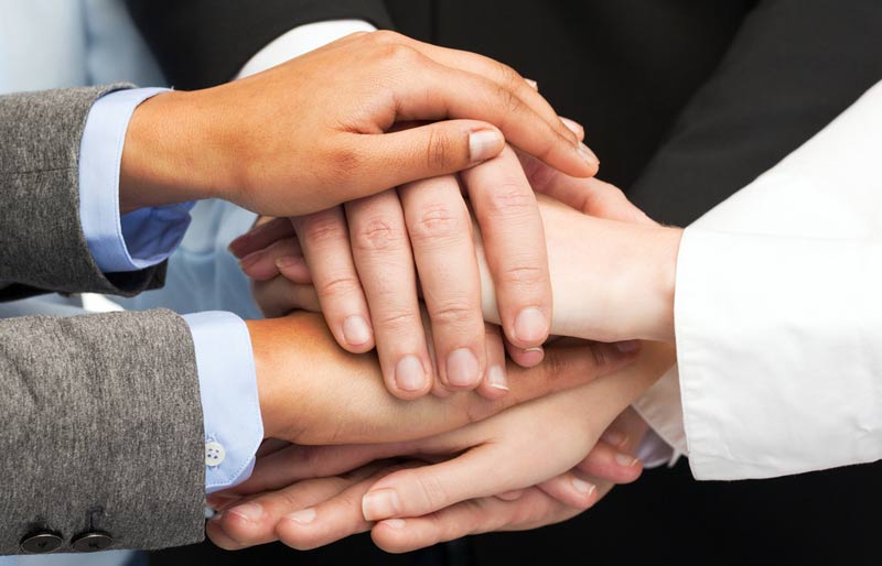 Les employés d’un organisme sans but lucratif mettent leurs mains les unes sur les autres pour symboliser leur cohésion