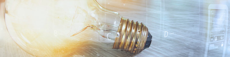 L’innovation et la stratégie sont illustrées par l’image d’une ampoule électrique allumée reposant sur un bureau où une personne travaille sur son ordinateur.