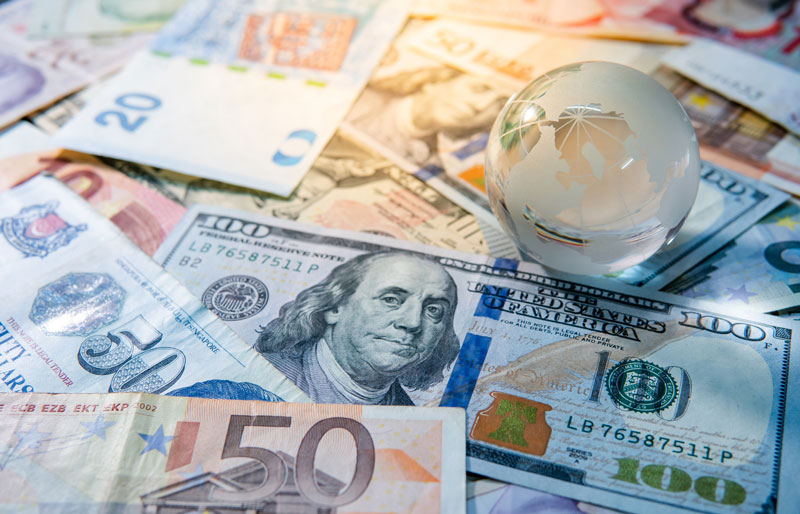 A selection of international currency on a table with a glass globe on top.