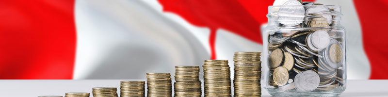 Image de piles de pièces de monnaie situées devant un drapeau canadien.